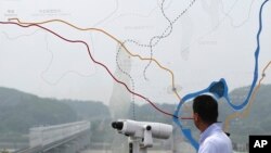 A man watches the north side through glass showing a map of the demilitarized zone between North and South Koreas near the truce village of Panmunjom, July 6, 2017.