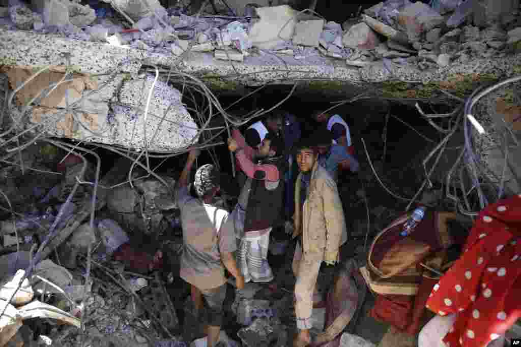 Orang-orang mencari korban yang masih hidup di bawah reruntuhan rumah yang hancur akibat serangan udara yang dipimpin oleh Arab Saudi yang menewaskan seorang sutradara TV, istrinya, dan ketiga anaknya di Sana&#39;a, Yaman.