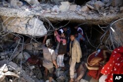 FILE - People search for survivors under the rubble of a house destroyed by Saudi-led airstrikes that killed a TV director, his wife, and three children in Sanaa, Yemen, Feb. 10, 2016.