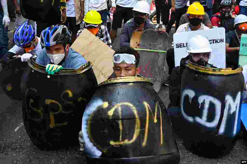 Protesters take cover behind homemade shields during a demonstration against the military coup in Yangon, Myanmar.