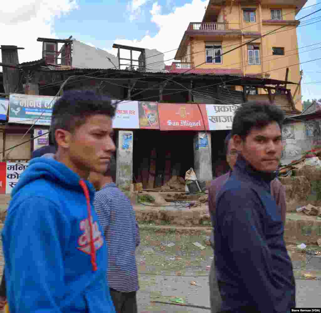 Dua pria muda berjalan melewati kehancuran di Melamchi di distrik Sindhupalchok.
