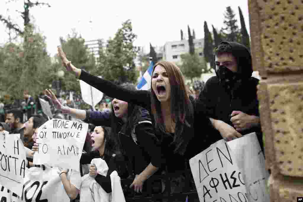 Cypriot students shout slogans as they stand at an entrance of the presidential palace in capital Nicosia, on March 26, 2013. The banner on the left reads in Greek " people fight they drink your blood".