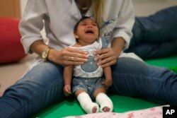 In this Feb. 4, 2016 photo, Luana Vitoria, who was born with microcephaly, cries during a physical therapy session at a treatment center in Racife, Brazil. (AP Photo)