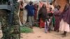 A Kenya Defense Force soldier walks past residents during a patrol in Ras Kamboni near the Somalia border, December 13, 2011.