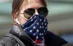 美国华盛顿一名妇女把星条旗图案的围巾当成口罩掩住口鼻。（2020年4月2日）