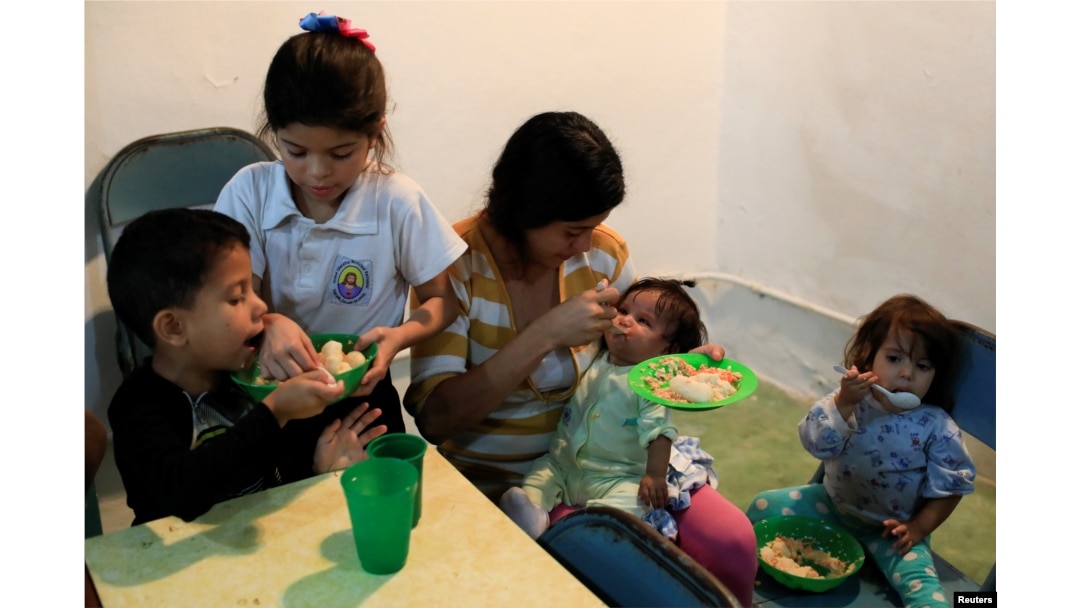 The children of Viviana Colmenares (C) have lunch in a community diner at the slum of Petare in Caracas, Feb. 22, 2018.
