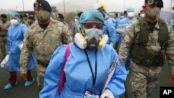 Des agents de santé escortés par des soldats lors d'une campagne de dépistage du coronavirus en porte-à-porte dans le bidonville de Villa Maria del Triunfo à Lima, au Pérou, le 12 janvier 2021.