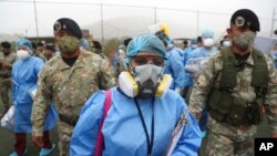 Les agents de santé sont escortés par des soldats lors d'une campagne de dépistage du COVID-19 porte-à-porte dans le bidonville Villa Maria del Triunfo de Lima, au Pérou, le mardi 12 janvier 2021. (Photo AP / Martin Mejia)