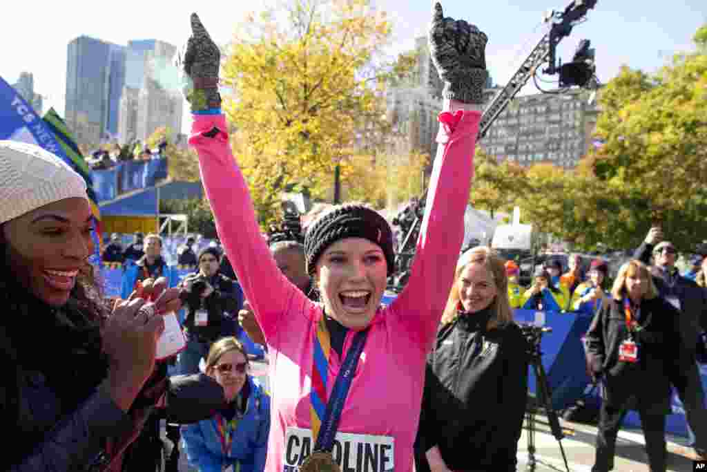 Tennis player Caroline Wozniacki raises her hands after getting a medal for completing the New York City Marathon in New York, Nov. 2, 2014.