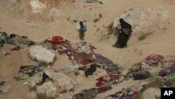A woman and her children, who left the besieged Islamic State-held village of Baghuz, Syria, scramble over a rocky hillside to be checked by U.S-backed Syrian Democratic Forces, March 14, 2019.