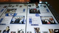 FILE - A visitor, top, looks at an electronic screen displaying images and convicted corruption charges of China's fallen politicians, Bo Xilai, bottom second right, Zhou Yongkang, bottom left, and other senior officials, at the China Court Museum in Beijing.