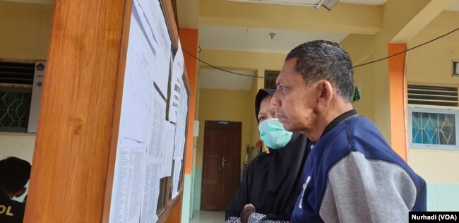 Warga melihat daftar nama 10 korban meninggal kegiatan susur sungai di SMPN 1 Turi, Sleman, Yogyakarta, 23 Februari 2020. Kejadian nahas itu terulang pada 11 siswa MTs Ciamis yang tewas karena susur sungai pada 15 Oktober 2021. (Foto:VOA/ Nurhadi)