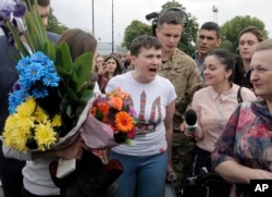 FILE - Ukrainian pilot Nadiya Savchenko, center, speaks to the media upon her arrival at Boryspil airport outside Kyiv, Ukraine, following her arrival from Russia in a prisoner swap, May 25, 2016.