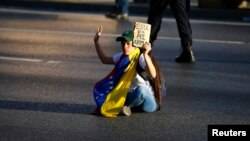 Una joven opositora se sienta para bloquear una calle en Caracas durante las protestas antigubernamentales de 2014.