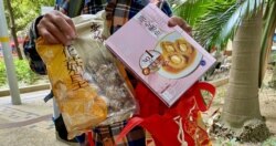 陈先生展示当局送赠的海味福袋内其中两件产品，包括花菇及即食鲍鱼 (美国之音/汤惠芸)