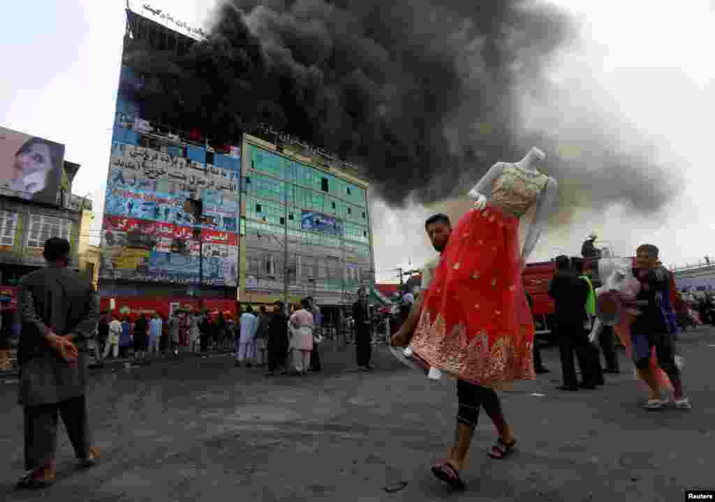 An Afghan shopkeeper carries a mannequin after a fire broke out a shopping mall in Kabul.