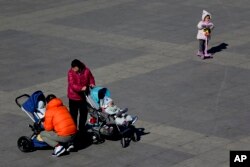 Sebuah keluarga bersama bayi-bayi mereka di taman di Beijing, 17 Februari 2019. (Foto: AP)