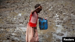 A girl walks through mud to get water at the Yusuf Batil refugee camp in Upper Nile, South Sudan, July 4, 2012.