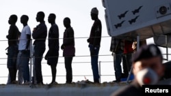 FILE - Migrants disembark from a navy ship in the Sicilian harbour of Pozzallo June 30, 2014.