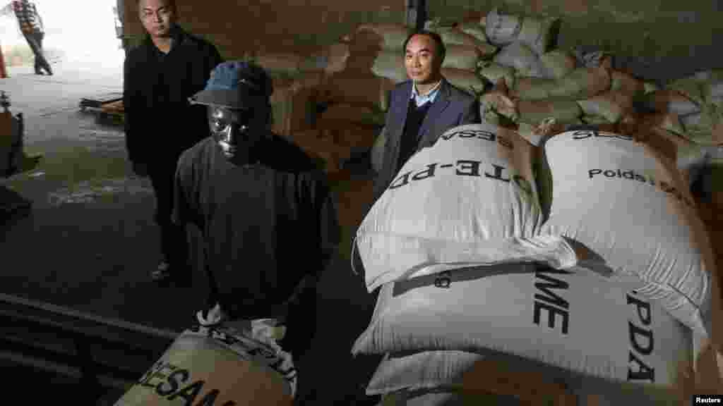 Riping Ouyang (d), investisseur chinois, supervise un travailleur sénégalais qui empile des sacs de graines dans une usine de transformation de sésame à Dakar, Sénégal, 11 février 2009.