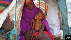 موغادیشو کے قریب ایک پناہ گزین کیمپ میں ایک صومالی عورت اپنے بیمار بچے کے ساتھ امداد کے انتظار میں بیٹھی ہے، اپریل 2017