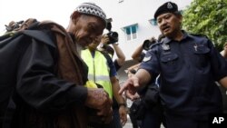 FILE - a police officer checks a man's identity in Kuala Lumpur, Malaysia.