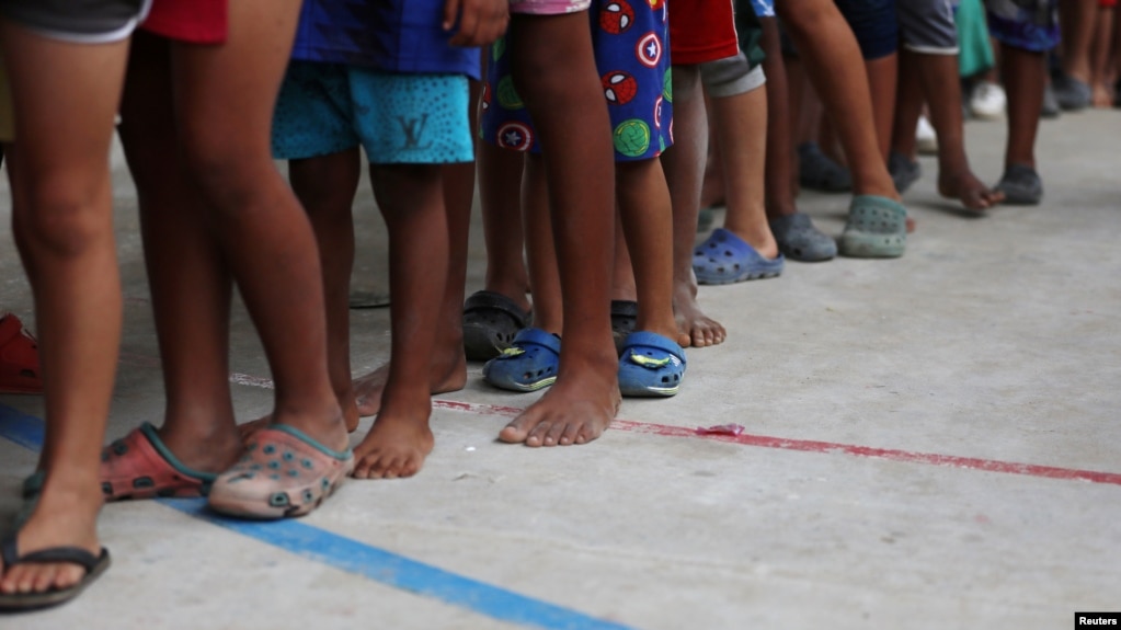 ARCHIVO - Niños migrantes venezolanos hacen fila dentro de un coliseo donde se ha instalado un campamento temporal, luego de huir de su país, según la agencia colombiana de migración, en Arauquita, Colombia, 26 de marzo de 2021.