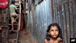 A Bangladeshi child stands in an alley as a boy climbs a ladder outside their home at a slum in Dhaka, Bangladesh, Oct. 17, 2014.