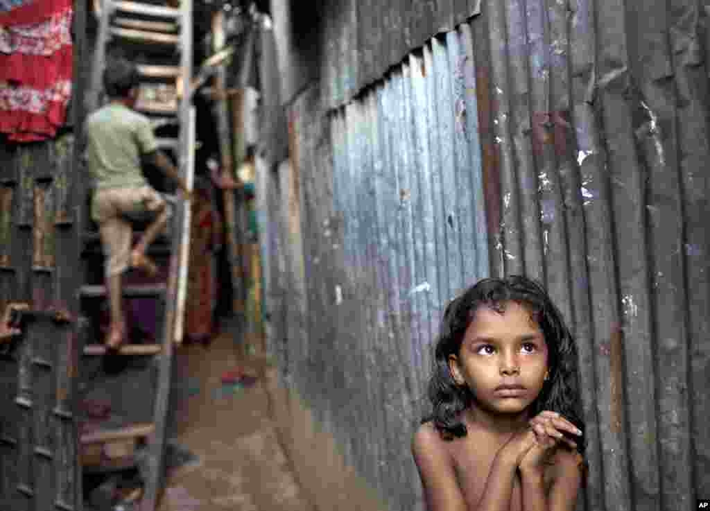 A Bangladeshi child stands in an alley as a boy climbs a ladder outside their home at a slum in Dhaka, Bangladesh. Oct. 17 is International Day for the Eradication of Poverty, designed to promote awareness of the need to put an end poverty in all countries.