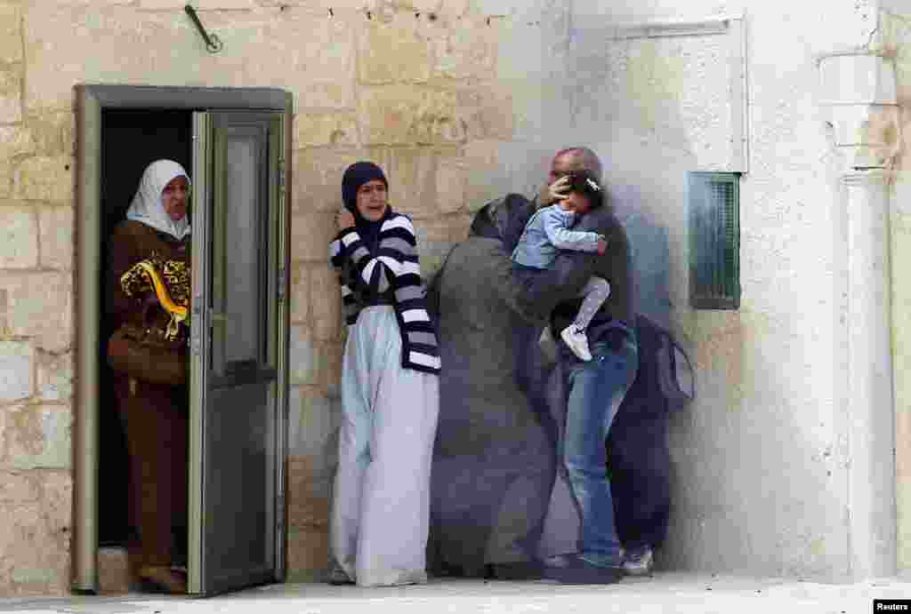 Palestinians react to tear gas fired by Israeli police during clashes after Friday prayers at a compound known to Muslims as al-Haram al-Sharif and to Jews as Temple Mount, in Jerusalem's Old City.