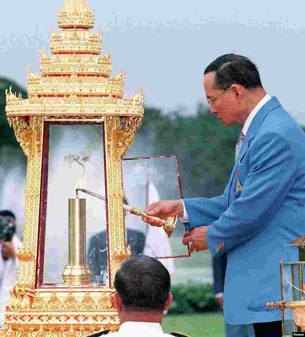 King Bhumibol lights the flame for the 13th Asian Games, Dec. 3, 1998, during a ceremony at Chitrlada Palace, the King&#39;s residence, during a ceremony three days prior to the start of the games.