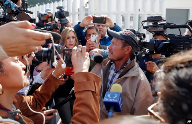 Carlos Catarldo Gomez, of Honduras, right, is surrounded by reporters after leaving the United States, the first person returned to Mexico to wait for his asylum hearing date, in Tijuana, Mexico, Jan. 29, 2019. The Trump administration has launched an effort to make asylum seekers wait in Mexico while their cases wind through U.S. immigration courts.