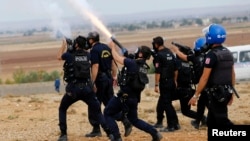 Turkish riot police fire tear gas to disperse pro-Kurdish protesters near the Turkish-Syrian border in the southeastern town of Suruc in Sanliurfa province, Sept. 29, 2014.