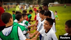 Des enfants israéliens et palestiniens se serrent la main lors d'un événement inaugurant une année de formation d'un programme de football israélo-palestinien lancé par le Centre Peres pour la paix, à Kibboutz Dorot, en dehors de la bande de Gaza, le 1er septembre 2014.