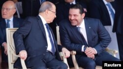 Saad al-Hariri talks with Lebanese President Michel Aoun while attending a military parade to celebrate the 74th anniversary of Lebanon's independence in downtown Beirut, Lebanon, Nov. 22, 2017.
