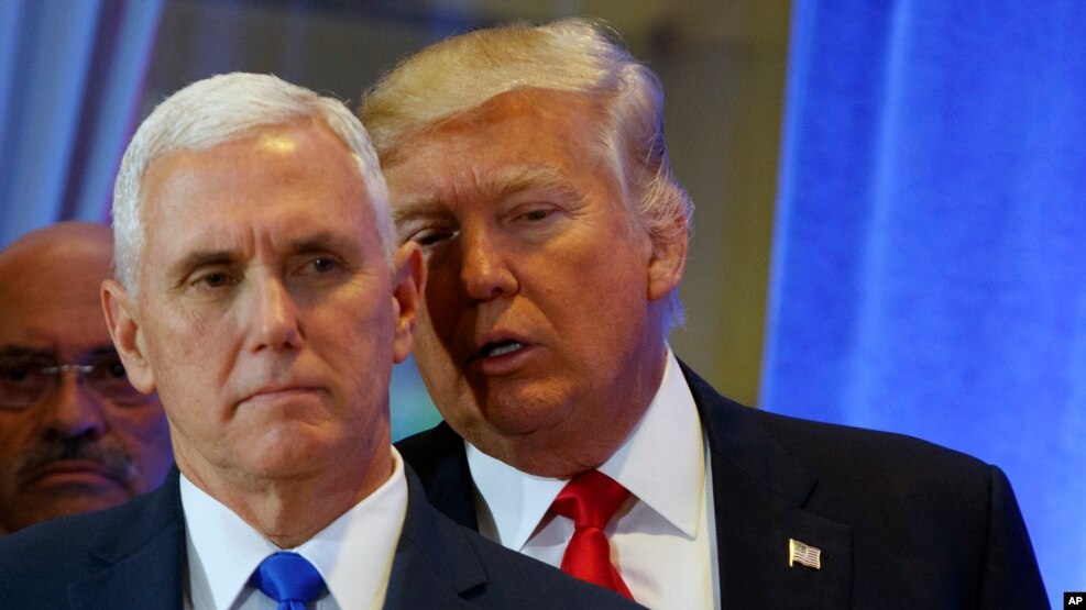 Le président élu des Etats-Unis Donald Trump, arrière-plan, soufle quelques choses à l’orielle de son vice-président Mike Pence lors d’une conference de presse à la tour Trump, à New York, 11 janvier 2017.