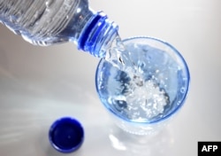 FILE - A glass is filled in with drinking water in Paris, April 27, 2014.