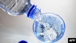 FILE - A glass is filled in with drinking water in Paris, April 27, 2014. Scientists have developed a box that can convert low-humidity air into water.