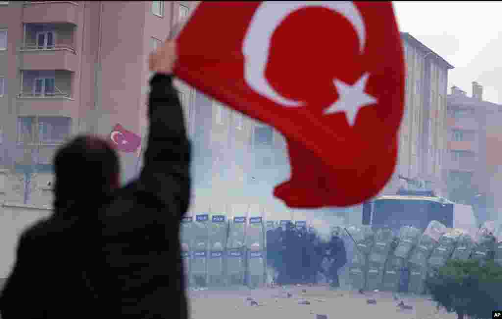 A man, holding a national flag with a poster of Turkey's founder Kemal Ataturk, watches as thousands of Turks clash with security as they try to break through barricades mounted around the prison and courthouse complex in Silivri, in the outskirts of Istanbul.