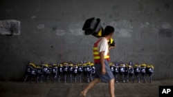 A road worker walks past flowers placed under a bridge where a man drowned July 21 in his flooded car on a main road in Beijing, July 27, 2012. 