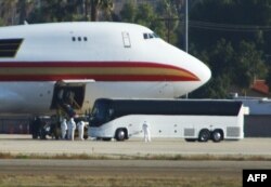 Personnel in biological hazard suits await passengers evacuated from Wuhan, the Chinese city at the heart of a growing outbreak of the deadly Novel Coronavirus shortly after the plane landed at March Air Reserve Base in Riverside, California.