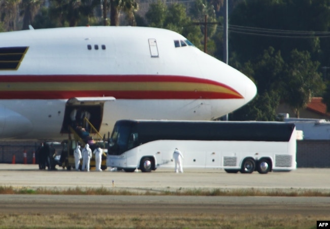 Personnel in biological hazard suits await passengers evacuated from Wuhan, the Chinese city at the heart of a growing outbreak of the deadly Novel Coronavirus shortly after the plane landed at March Air Reserve Base in Riverside, California.