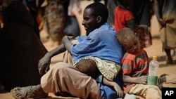 A Somali man who fled violence and drought in Somalia with his family sits on the ground outside a food distribution point in the Dadaab refugee camp in northeastern Kenya on July 5, 2011