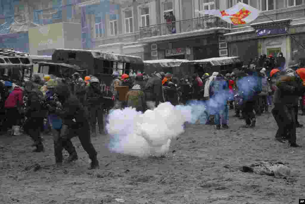 Manifestantes fogem após o rebentamento de uma granada durante os confrontos com a polícia no centro de Kiev, Jan. 22, 2014. 