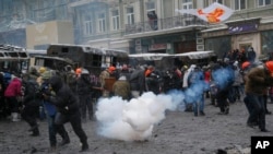 Protesters run away from a stun grenade as they clash with police in central Kyiv, Jan. 22, 2014. 