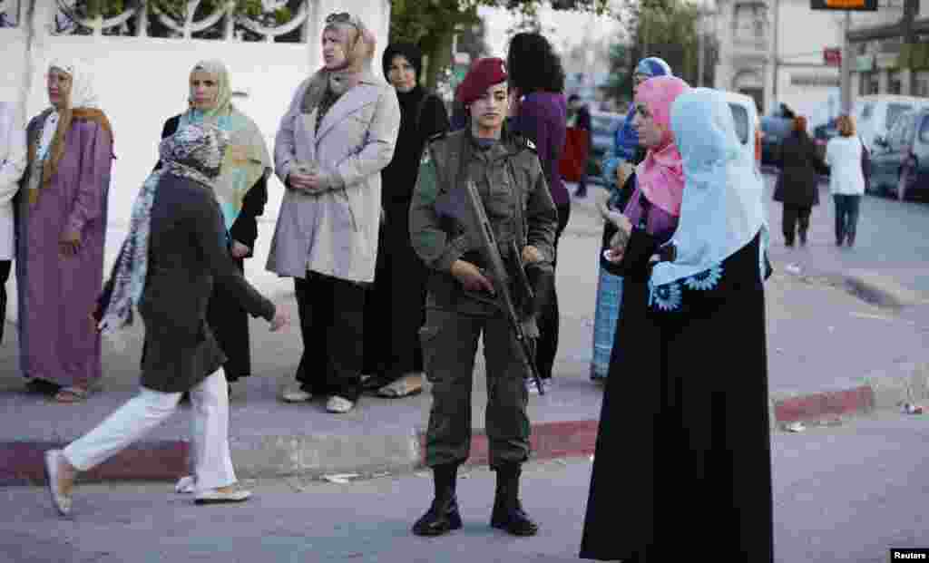 People stand in line at a polling station as they wait to cast their votes, in Tunisia, Oct. 26, 2014. 