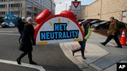 Demonstranti nose simbolični budilnik na kome piše "Neutralnost interneta" na protestu ispred Federalne komisije za komunikacije u Vašingtonu.