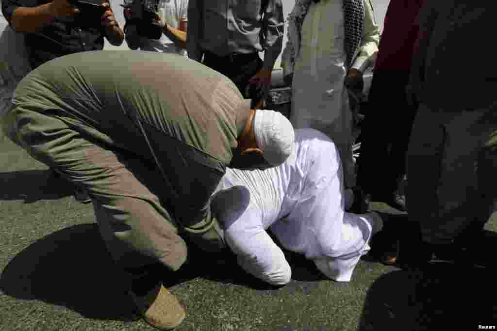 Abu Qatada kneels at the feet of his father after his release, Amman, Sept. 24, 2014. 