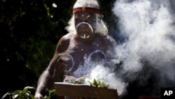 FILE - An aboriginal elder performs a ceremony during an official function at Sydney Harbor, Australia, Nov. 27, 2013. A new map documents massacres of aboriginees following the arrival in Australia of British colonists in the late 18th century.