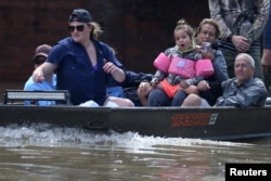 People ride a boat though flood water after being evacuated from the rising water following Hurricane Harvey in a neighborhood west of Houston, Texas, Aug. 30, 2017.